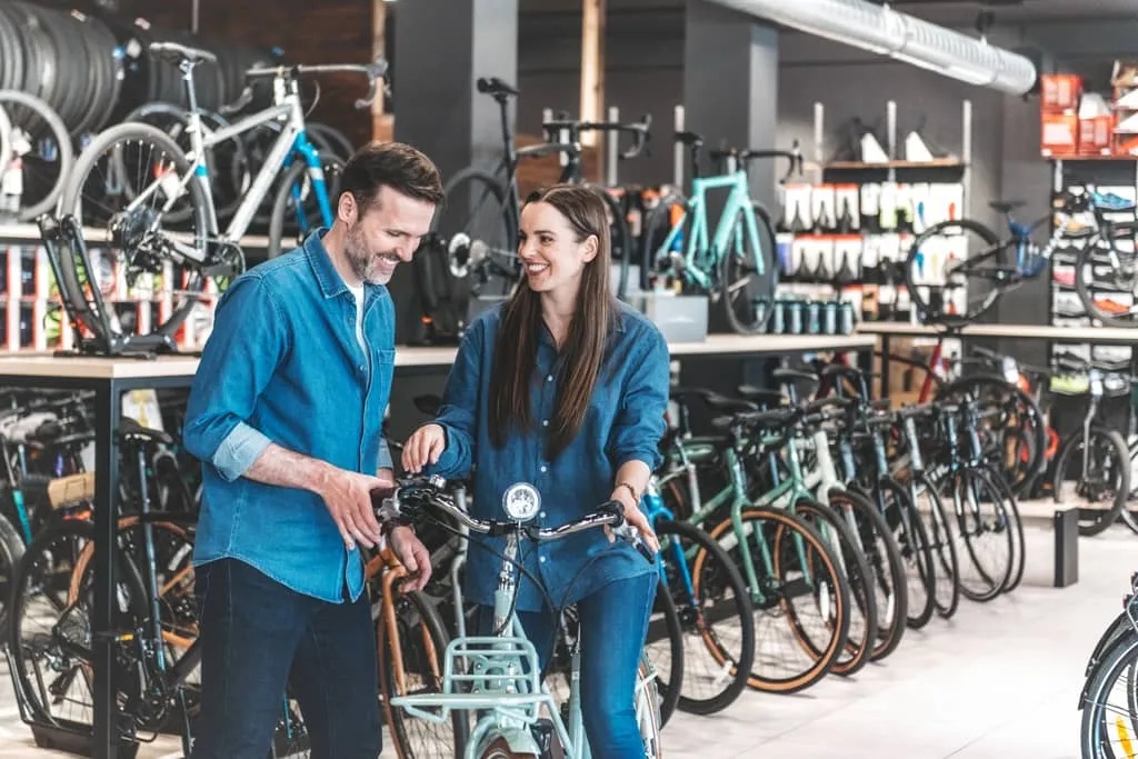 voucher process, Woman sitting on an e-bike in a bike shop, man tests the hand brake.