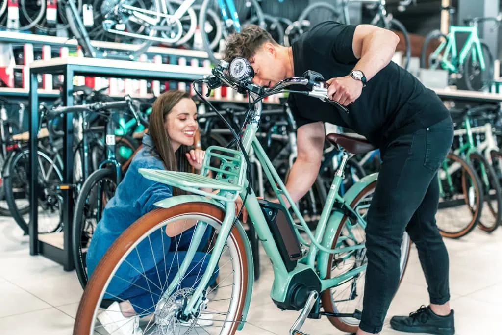 man and woman at a bike shop, looking over a green e-bike.